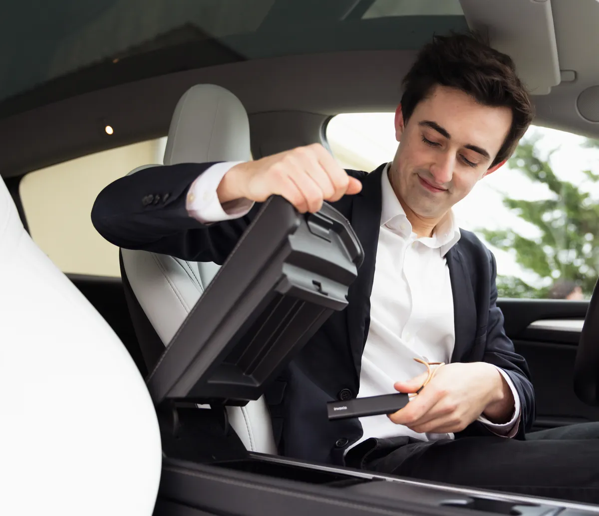Un homme calme en costume plaçant un Classic GPS Tracker dans la console centrale de sa voiture