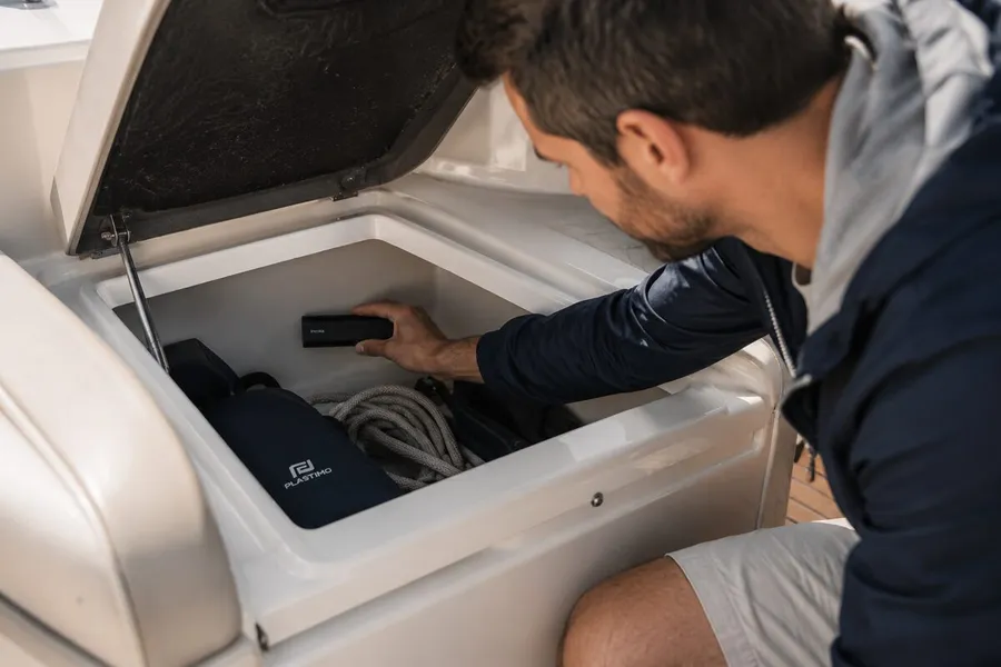 Un homme place un GPS Tracker Pro Max dans un coffre de rangement de bateau