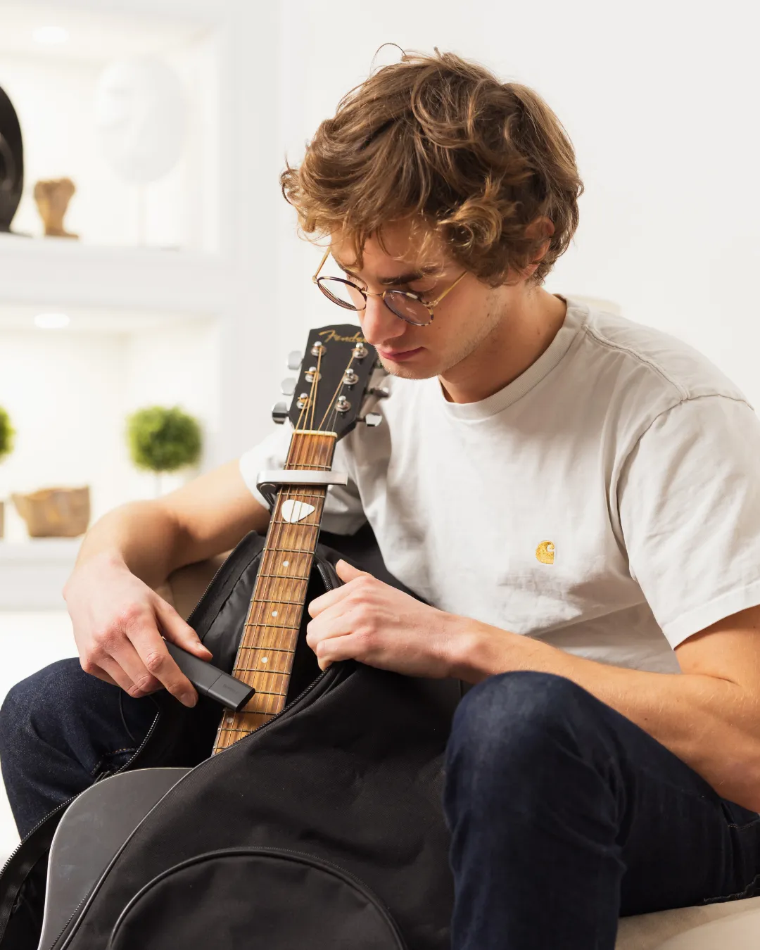 Un jeune homme cache un Tracker GPS Classic dans un étui de guitare