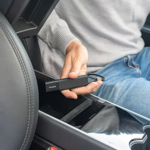 a person hiding their Tracker GPS Pro inside a car’s center armrest