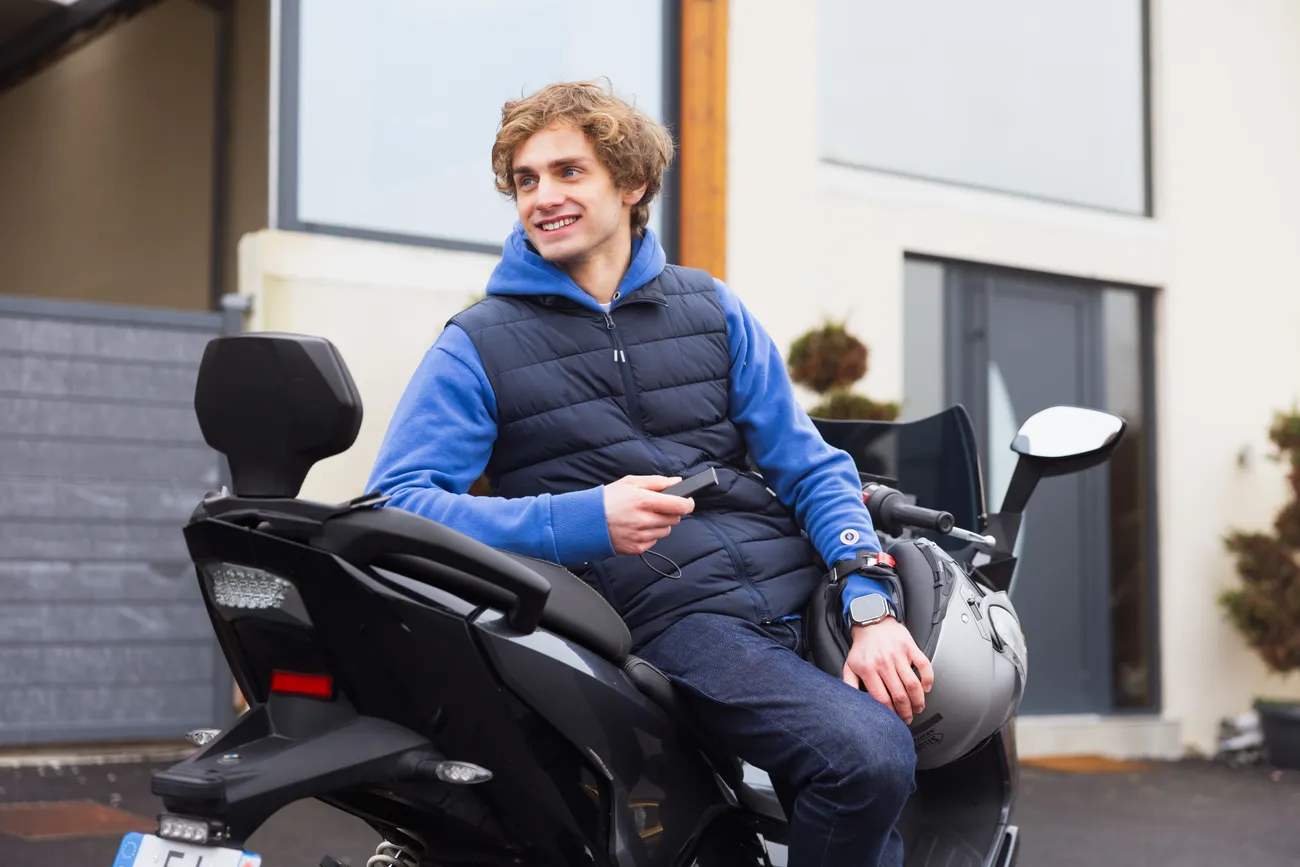 Homme sur un scooter tenant un Tracker GPS Pro dans la main