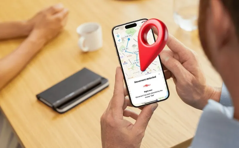 Un homme assis à une table reçoit une notification d'alerte de mouvement sur son application GPS Invoxia.