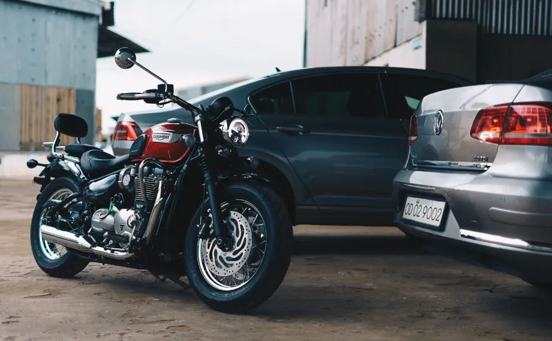 Une cour avec une moto de collection et 2 voitures.