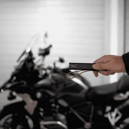 An Invoxia GPS Tracker in front of a motorbike