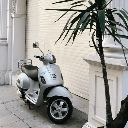 A scooter parked in front of a closed garage