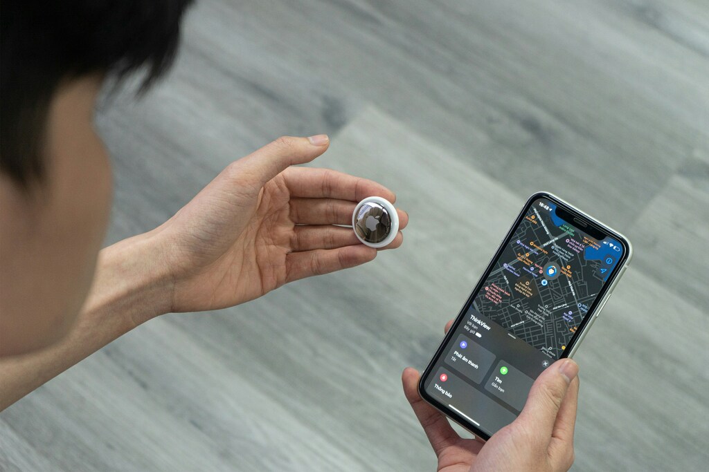 Image 2: Personne tenant un AirTag dans une main et son téléphone avec la carte GPS dans l&rsquo;autre