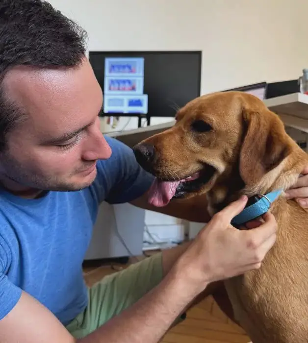 Un ingeniero de Invoxia con un perro equipado con el Biotracker