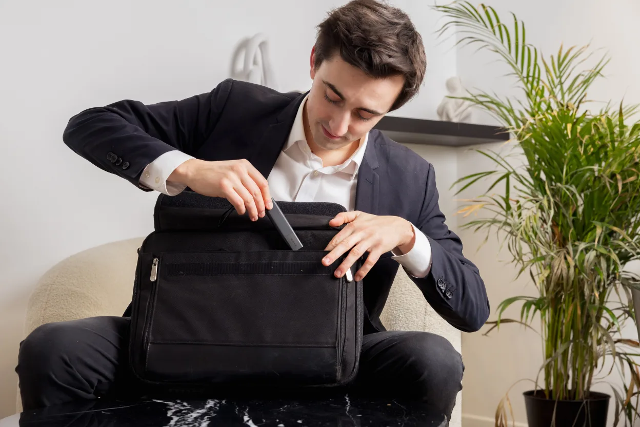 Man slipping an Invoxia GPS tracker into a laptop bag